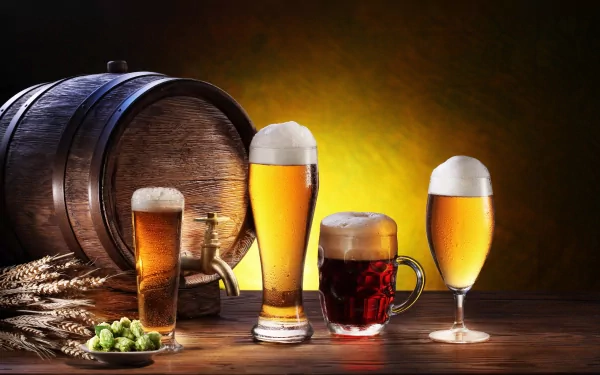 A collection of various beer glasses sits on a wooden table, with a rustic barrel in the background, showcasing a rich and inviting display of food and beer.