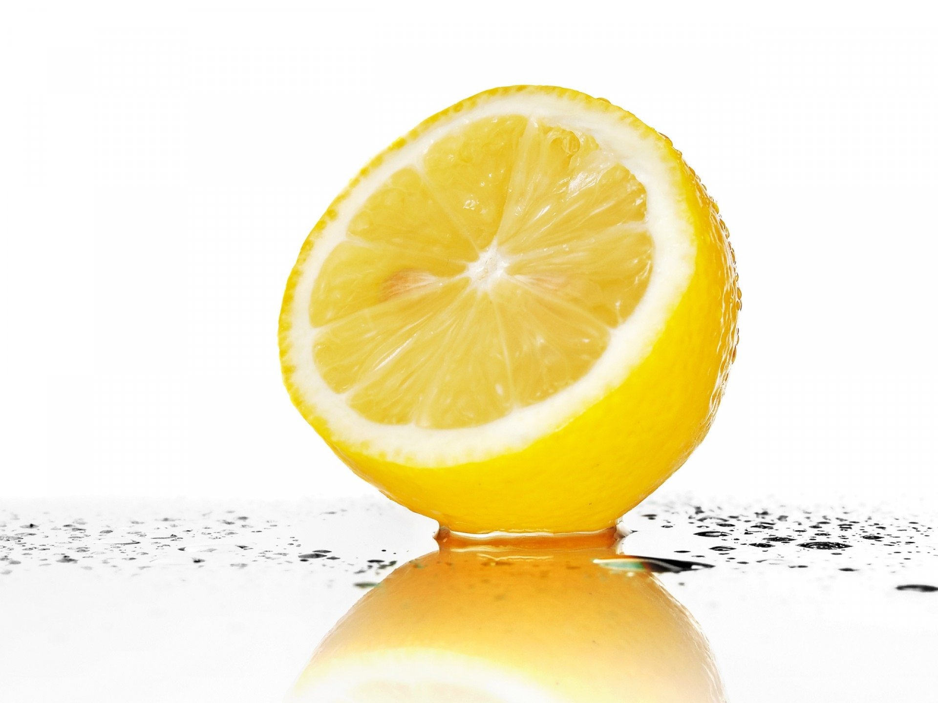 HD desktop wallpaper featuring a close-up of a fresh lemon half with water droplets, highlighting vibrant yellow tones and clean white background. Tags: banana, food, lemon.