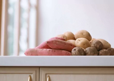 A vibrant collection of potatoes and sweet potatoes arranged on a countertop, showcasing their natural textures and colors in this HD desktop wallpaper.