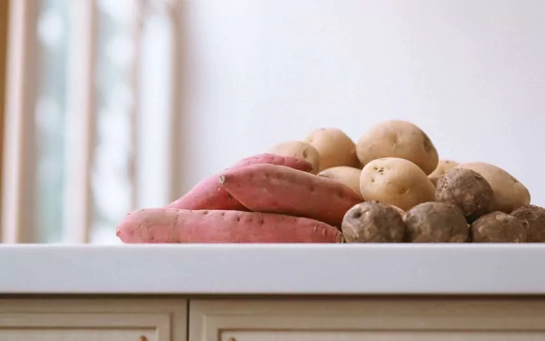 A vibrant collection of potatoes and sweet potatoes arranged on a countertop, showcasing their natural textures and colors in this HD desktop wallpaper.
