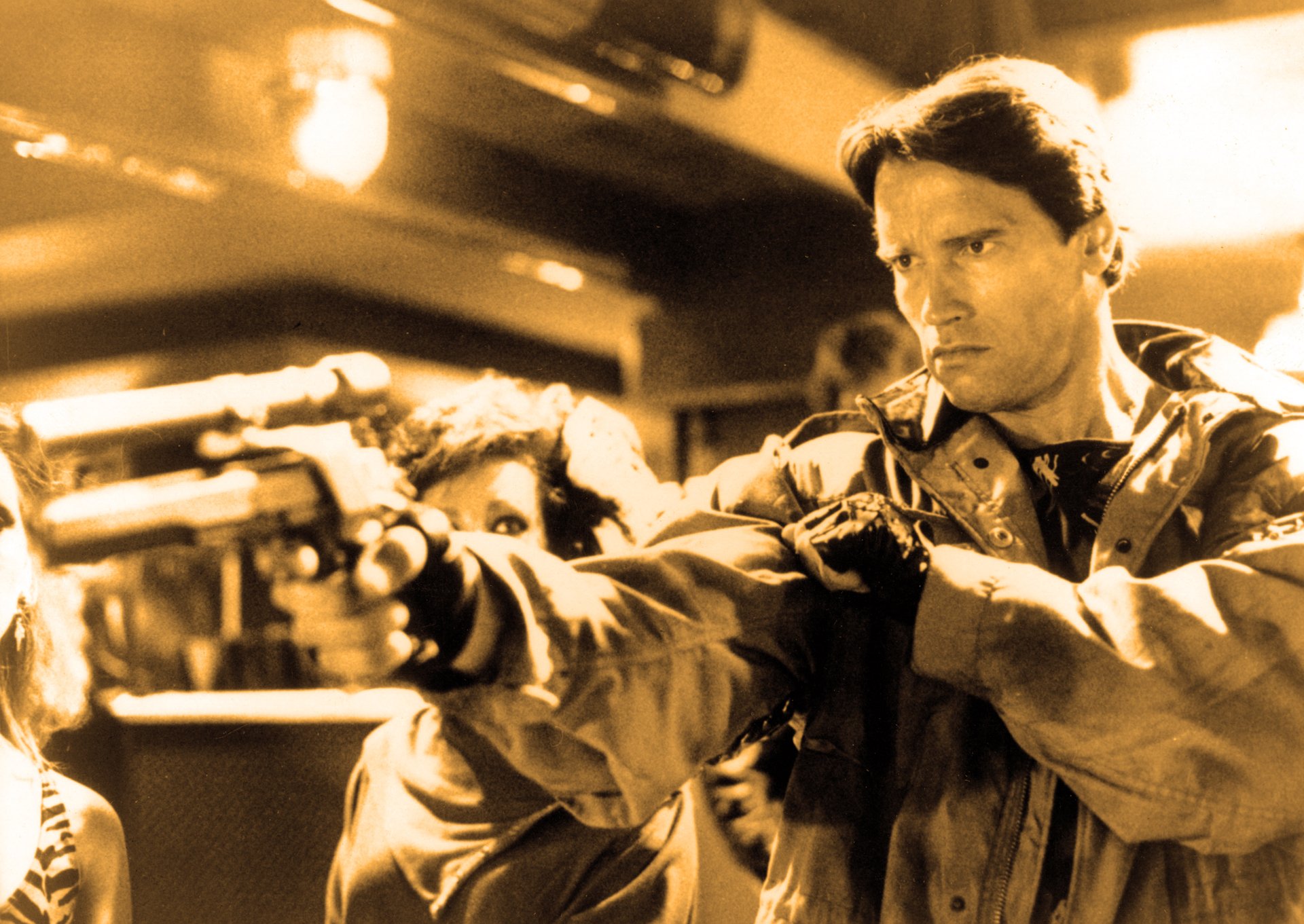 HD wallpaper featuring a dramatic scene from the movie The Terminator, showcasing a focused character aiming a firearm in a tense moment.