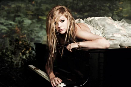 Avril Lavigne poses on a piano, draped in a flowing gown, set against a lush background. This striking image serves as a vibrant HD desktop wallpaper.