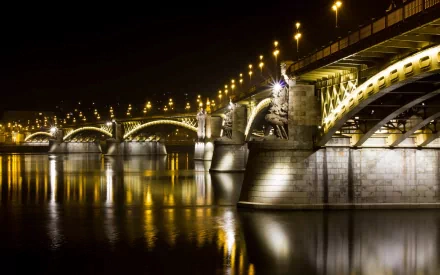 Night view of the illuminated Margaret Bridge in Budapest, Hungary, reflecting on the Danube River in this HD desktop wallpaper.