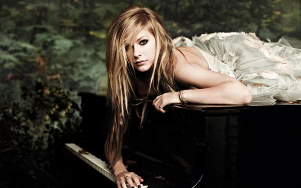 Avril Lavigne poses on a piano, draped in a flowing gown, set against a lush background. This striking image serves as a vibrant HD desktop wallpaper.