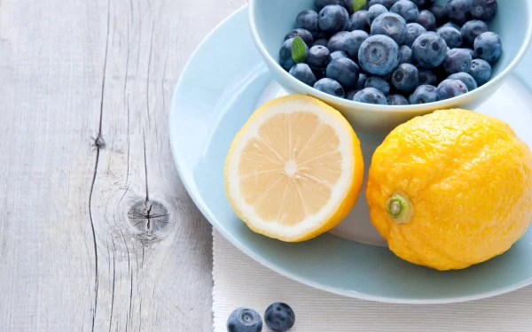 A 4K Ultra HD desktop wallpaper featuring fresh blueberries in a bowl alongside whole and halved lemons on a rustic wooden surface.