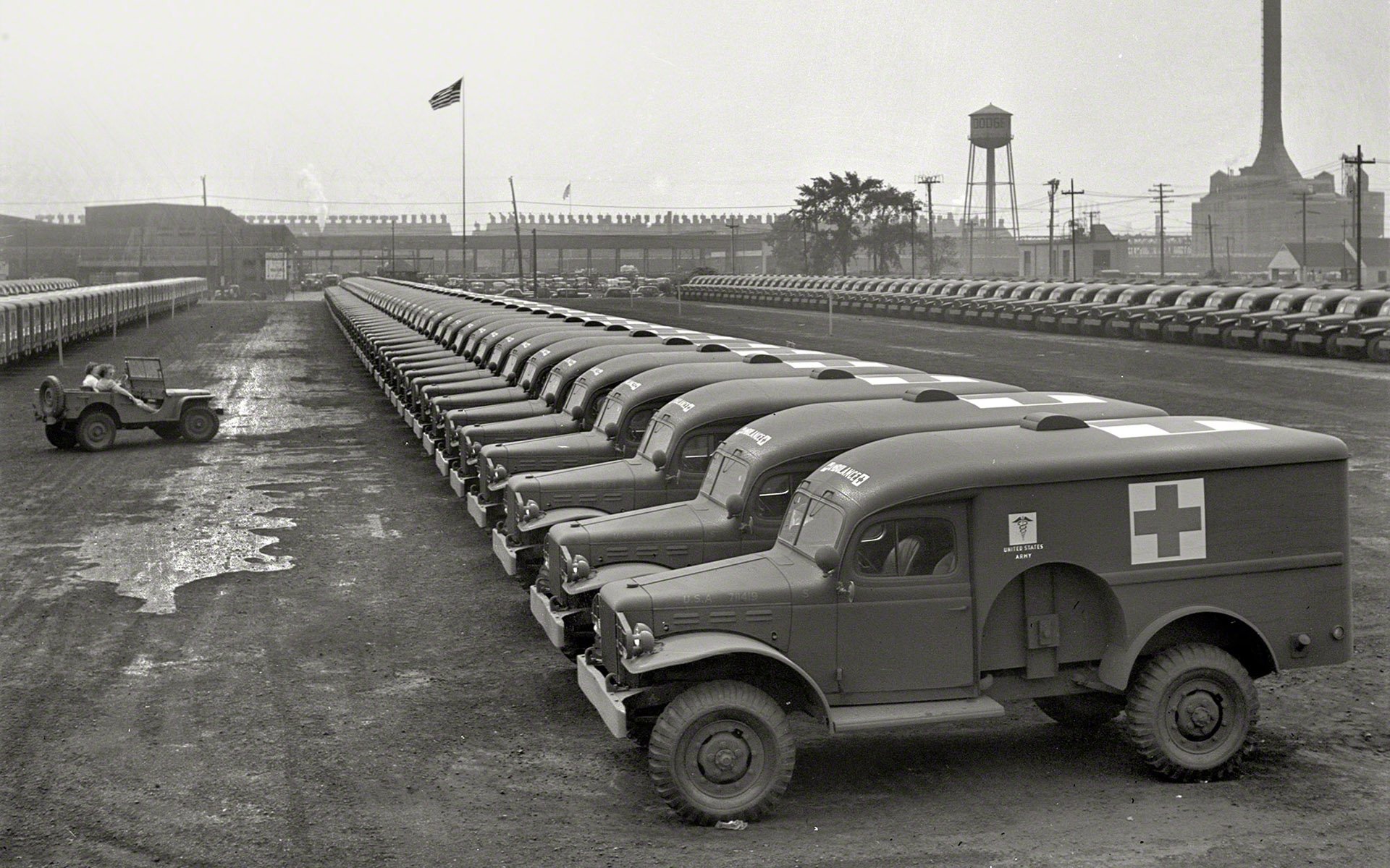 HD PC desktop wallpaper and background showing vintage military ambulances lined up in black-and-white at a depot with a flag and water tower.