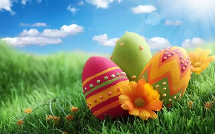 HD PC desktop wallpaper featuring colorful Easter eggs and vibrant flowers on green grass under a bright blue sky, celebrating the holiday.