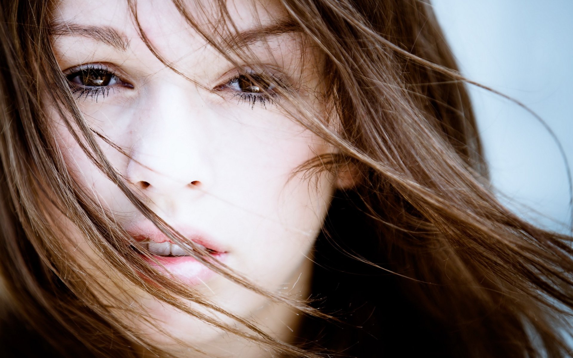 A close-up of a beautiful woman with flowing hair, captured in a moment that highlights her expressive features. This HD image serves as an engaging desktop wallpaper.