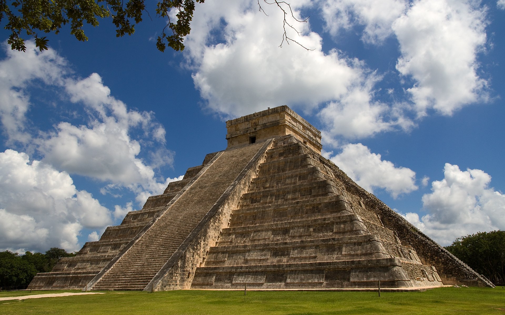HD desktop wallpaper featuring a man-made ancient pyramid under a bright blue sky with scattered white clouds.