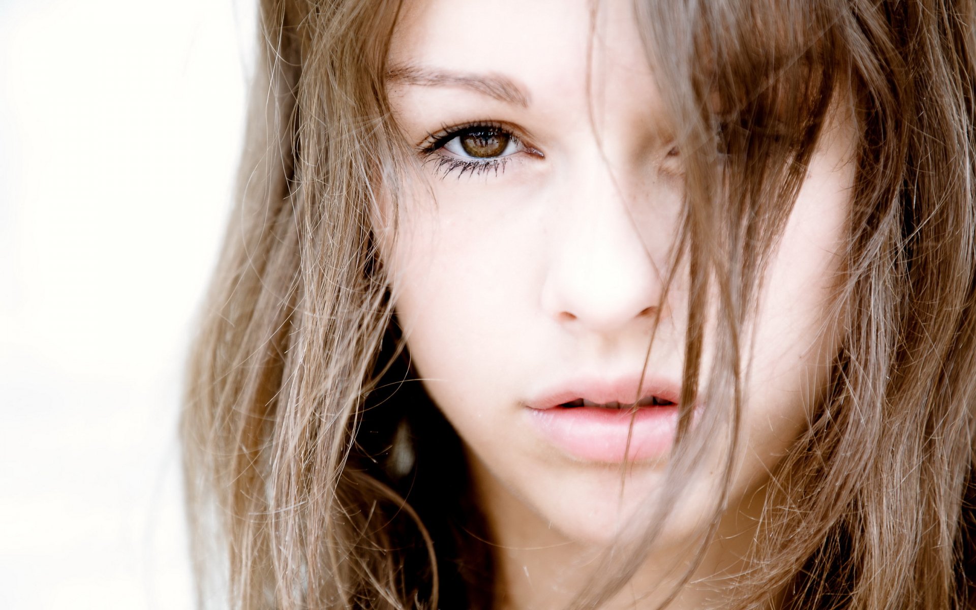 A close-up of a woman with tousled hair, capturing an intense gaze. This image serves as a striking HD desktop wallpaper and background.