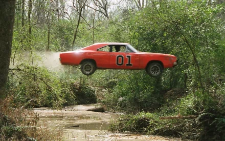 HD PC desktop wallpaper/background: The Dukes of Hazzard orange 01 Charger jumping over a wooded creek, captured midair.