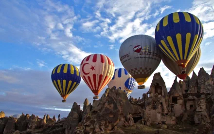 A vibrant scene featuring colorful hot air balloons soaring over rocky terrain under a blue sky. This HD wallpaper beautifully captures the essence of adventure and exploration.