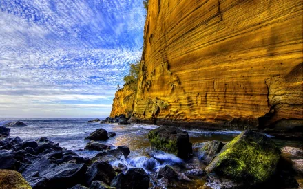 HD PC desktop wallpaper showcasing a dramatic rocky cliff beside the ocean under a vibrant sky, highlighting the beauty of nature's rugged coastline.