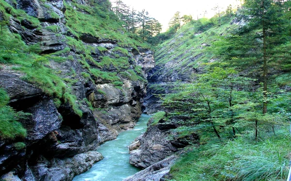 HD PC desktop background: turquoise river winding through a rocky, tree-lined gorge in Tirol, Austria, lush green nature.