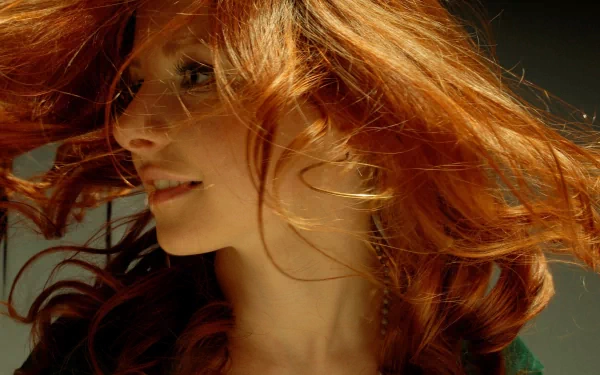 A woman with vibrant, flowing red hair is captured in motion, exuding confidence and energy. This striking image serves as an engaging HD desktop wallpaper and background.
