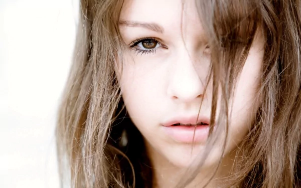 A close-up of a woman with tousled hair, capturing an intense gaze. This image serves as a striking HD desktop wallpaper and background.
