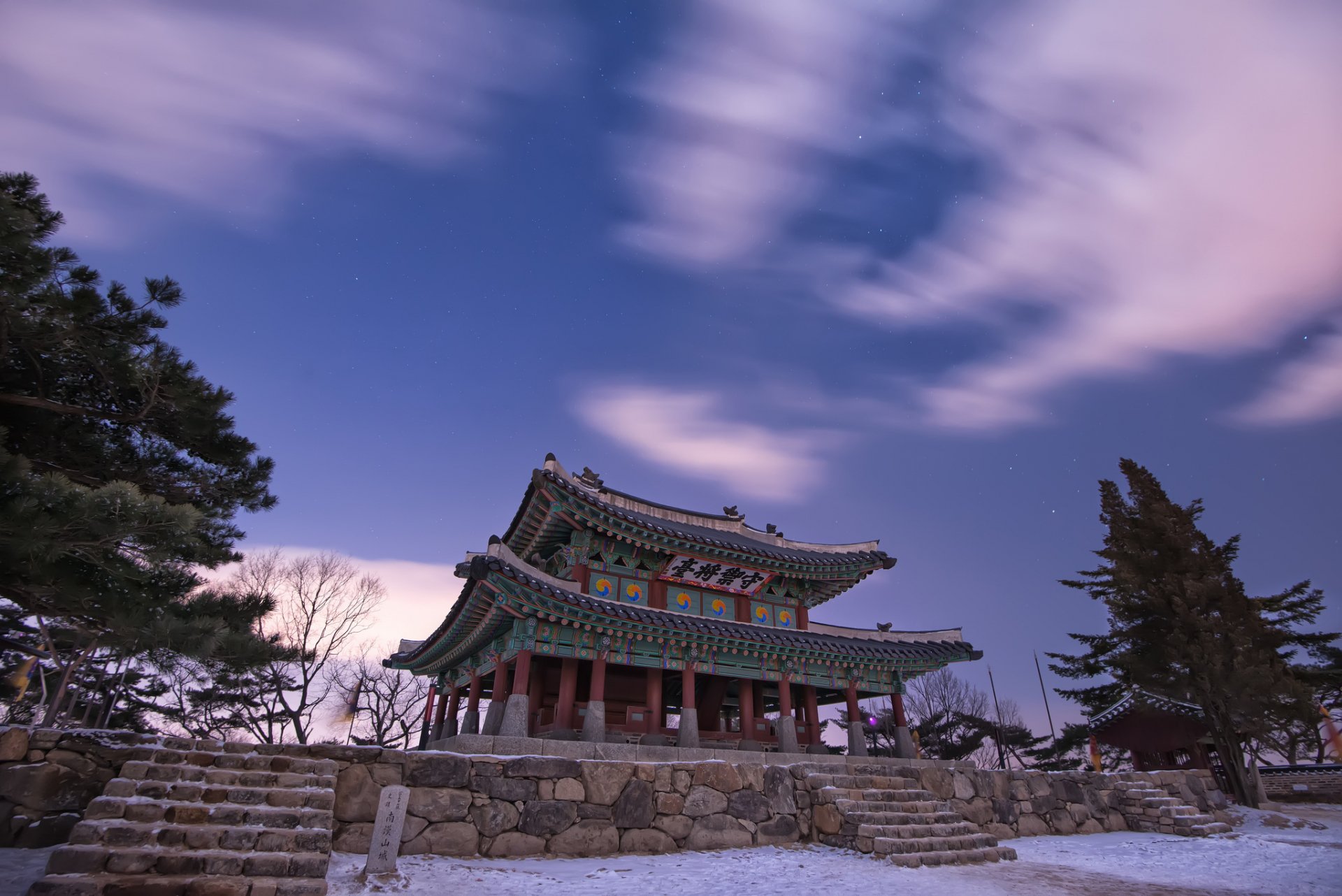HD desktop wallpaper featuring a traditional religious pagoda under a dynamic sky with clouds, framed by trees, capturing serene cultural architecture.