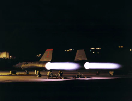 HD desktop wallpaper featuring two Lockheed SR-71 Blackbird military jets with afterburners blazing on a dark runway at night.