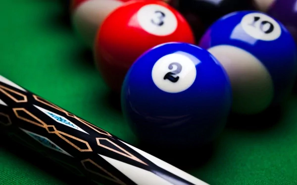 A close-up of a pool cue on a green felt table, with colorful billiard balls, showcasing the classic game atmosphere in a vibrant HD desktop wallpaper.