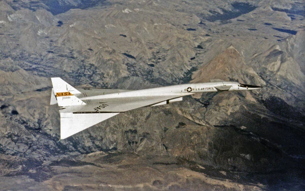 Military North American XB-70 Valkyrie supersonic prototype flying over rugged mountains — 2K Quad HD PC desktop wallpaper/background.