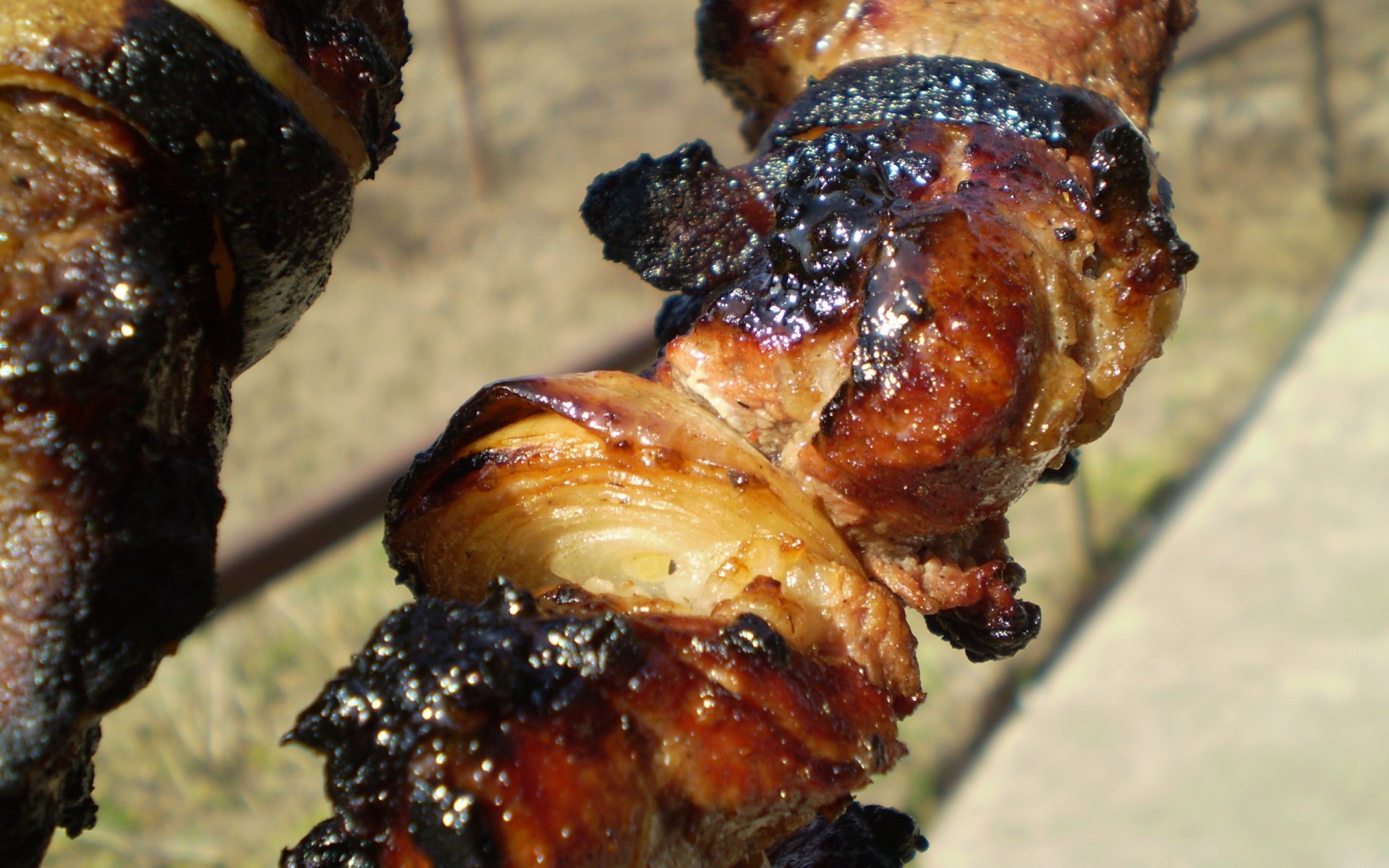 Close-up of sizzling barbecue skewers with grilled meat and onions, featured as an HD PC desktop wallpaper and background.