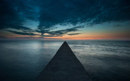 A serene pier extends into calm waters, set against a dramatic sky at dusk. This HD wallpaper captures the beauty of nature and man-made structures in harmony.