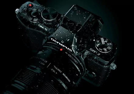 A close-up view of a sleek Olympus camera covered in water droplets, set against a dark background, creating a striking HD desktop wallpaper and background.