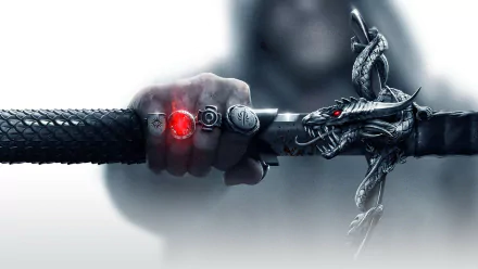 A dramatic HD wallpaper from Dragon Age: Inquisition, featuring a hand holding a sword adorned with a dragon design and glowing red gem, embodying the epic fantasy of the video game.