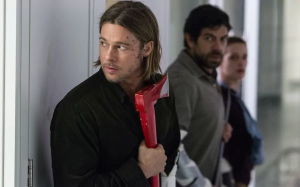 HD desktop wallpaper from the movie World War Z, showing a tense scene with Brad Pitt holding a red axe, with two men standing behind him in a corridor.
