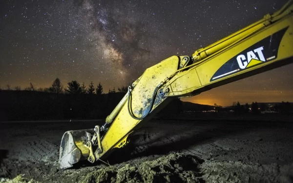 HD desktop wallpaper featuring a yellow Caterpillar Inc. vehicle's arm and bucket under a starry night sky with the Milky Way visible.