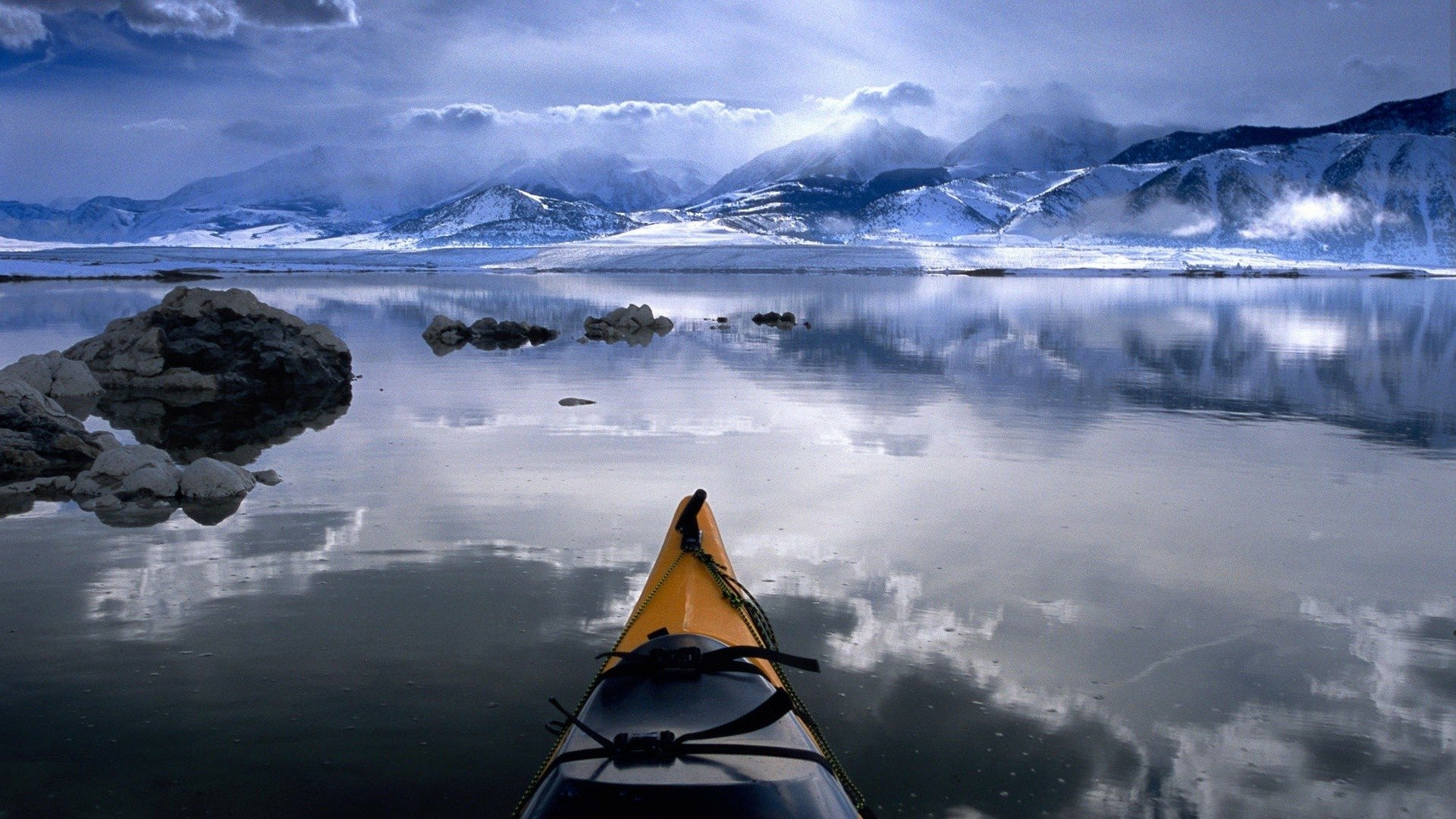 HD desktop wallpaper featuring a photography shot of a kayak on calm water with mountain and cloud reflections, capturing serene natural beauty.