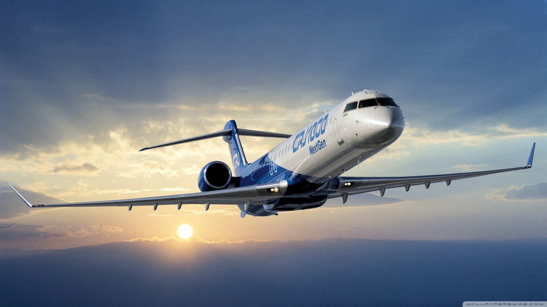Bombardier CRJ1000 vehicle — regional jet banking over clouds at sunset, 2K Quad HD PC desktop wallpaper/background.
