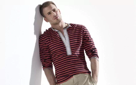 A high-definition desktop wallpaper featuring Chris Evans, showcasing him in a stylish striped shirt, leaning against a wall with a confident expression.