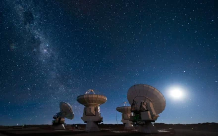 2K Quad HD desktop wallpaper: Milky Way, moon and stars above an array of man-made radio telescopes/radar dishes aimed at the galaxy.