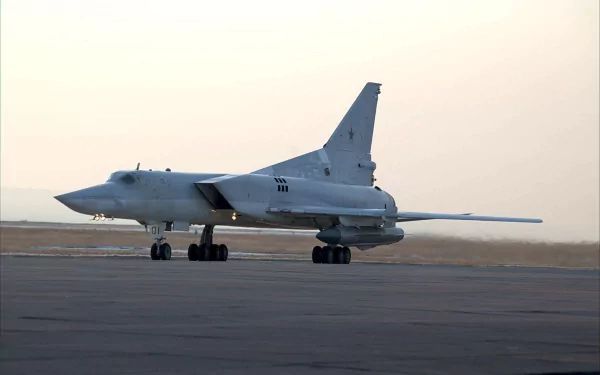 HD desktop wallpaper featuring a military Tupolev Tu-22 bomber parked on a runway at dusk with a pale sky background.