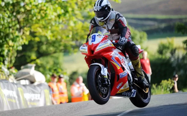 HD PC Desktop Wallpaper and Background: red racing motorcycle (vehicle) airborne on a country road, rider in full gear, blurred spectators and green landscape.