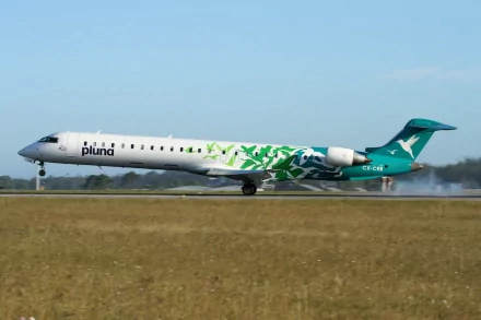 HD desktop wallpaper of a Bombardier CRJ700 aircraft with Pluna livery taxiing on a runway under a clear sky.