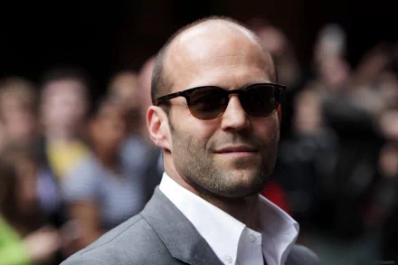 Jason Statham poses confidently in sunglasses, exuding a cool charisma, captured in this HD desktop wallpaper and background.
