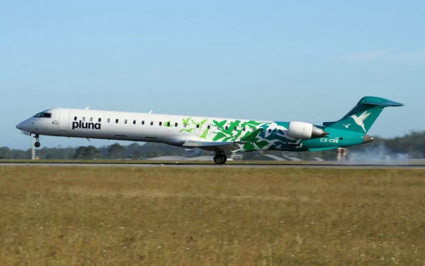 HD desktop wallpaper of a Bombardier CRJ700 aircraft with Pluna livery taxiing on a runway under a clear sky.