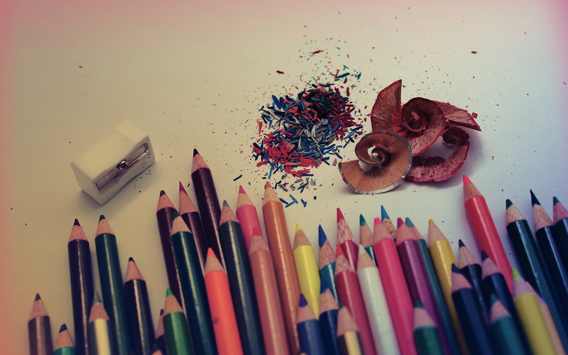 HD PC desktop wallpaper featuring a close-up photography of colorful pencil tips, sharpenings, and an eraser arranged on a light surface with pencil shavings scattered around.