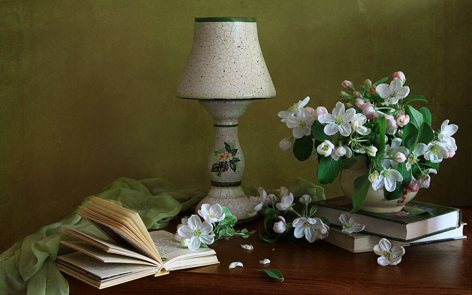 A still life composition featuring a lamp, an open book, and a vase of flowers, set against a soft green backdrop, creating a serene and elegant HD desktop wallpaper.