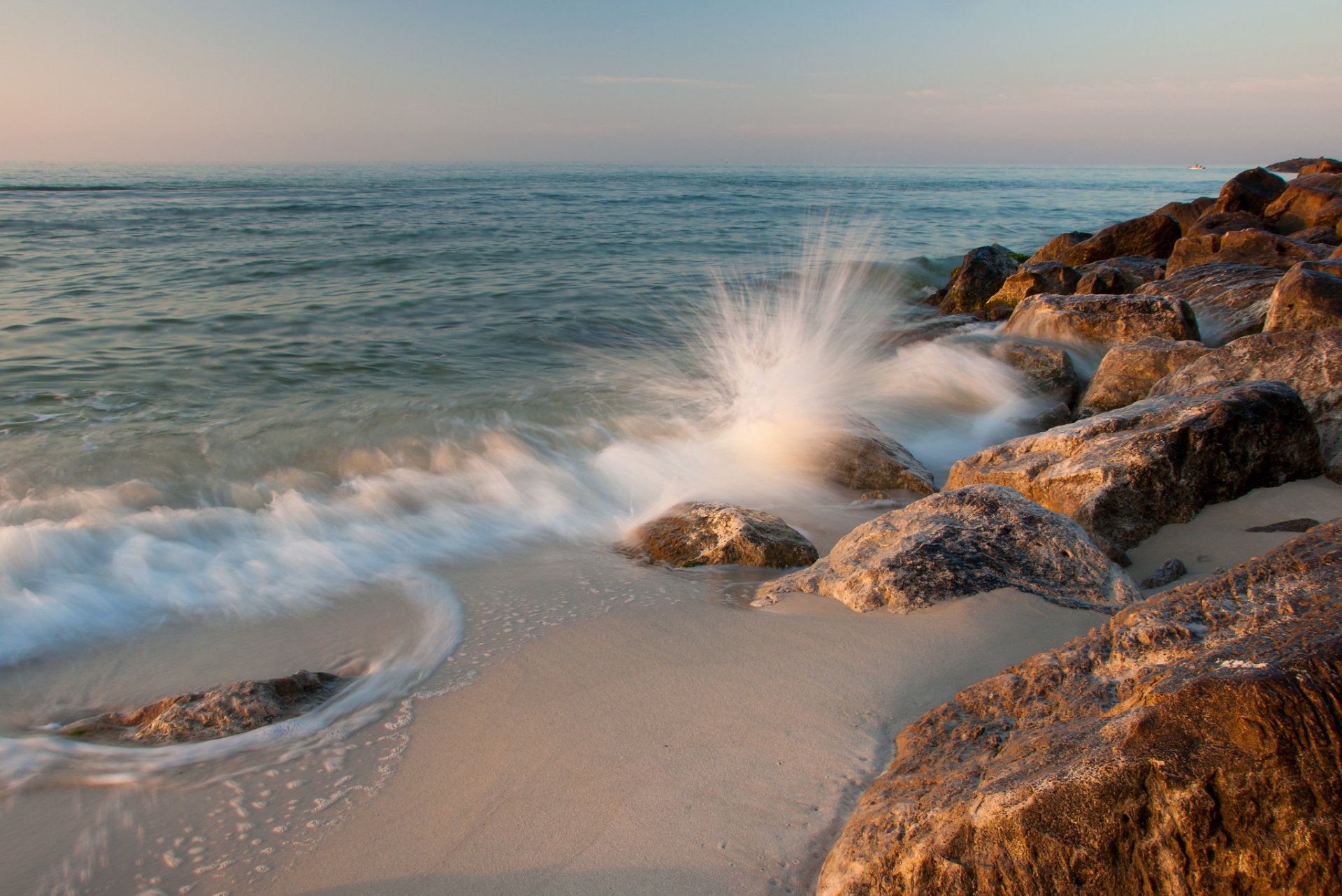 HD PC desktop wallpaper showcasing nature with ocean waves crashing against rocky shore during a calm sunset.