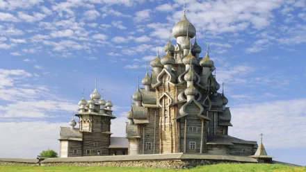 HD desktop wallpaper of the Church of the Transfiguration, a religious wooden structure with multiple onion domes under a blue sky with scattered clouds.