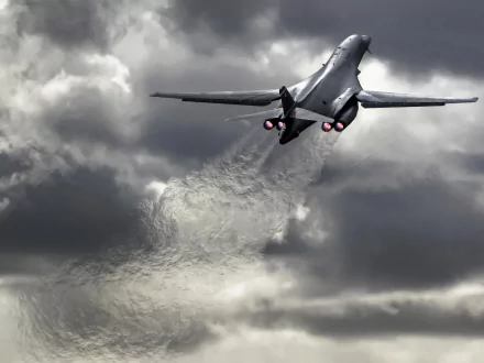 HD desktop wallpaper featuring a Rockwell B-1 Lancer military bomber ascending against a dramatic, cloudy sky with afterburners glowing.