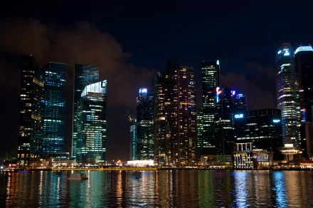 4K Ultra HD wallpaper of Singapore’s man-made skyline at night, featuring illuminated skyscrapers reflecting on the water.