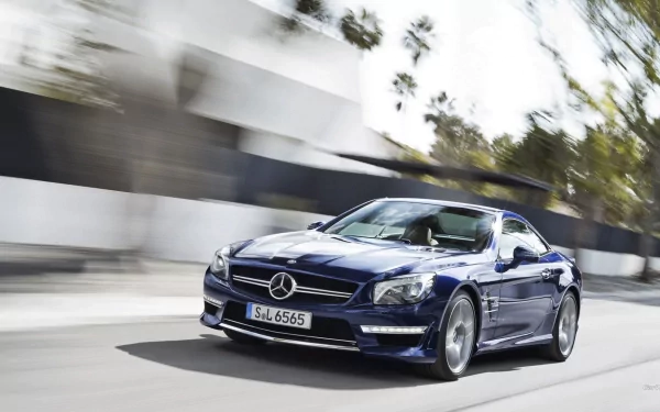 HD PC desktop wallpaper background showing a blue Mercedes-Benz SL65 speeding along a sunlit urban road, a sleek coupe captured in motion with blurred surroundings.