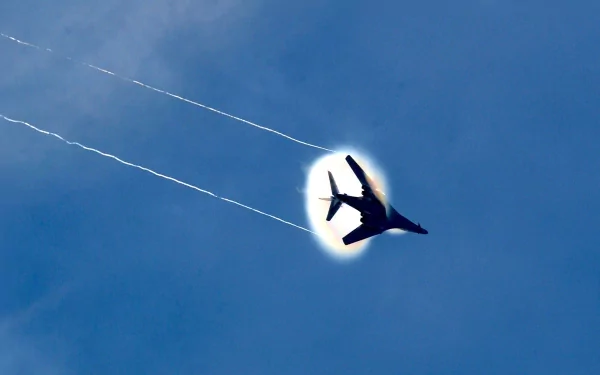 Rockwell B-1 Lancer military bomber captured in flight against a clear blue sky, creating condensation trails with a bright halo effect, featured as an HD desktop wallpaper.
