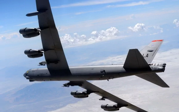 A Boeing B-52 Stratofortress in flight, showcasing its distinctive design amidst a backdrop of clouds and blue sky. An impressive military aircraft wallpaper.