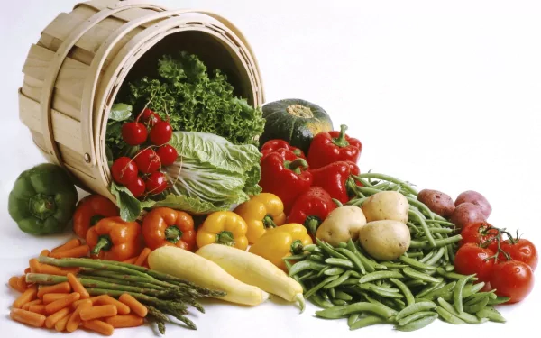 HD desktop wallpaper featuring an assortment of fresh vegetables, including tomatoes, carrots, and green beans, spilling from an overturned basket.