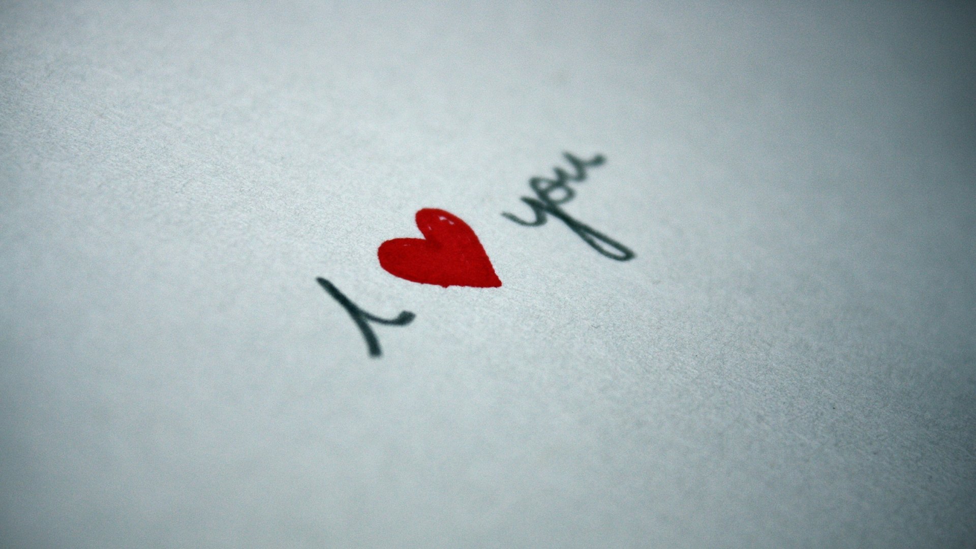 A close-up of the phrase I ❤️ you hand-written on textured paper, showcasing an artistic expression of love. This HD wallpaper adds a heartfelt touch to any desktop background.